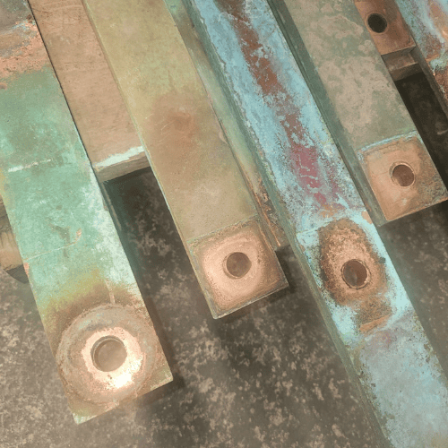 Gestion des déchets 65 Une vue en gros plan légèrement plus large et sous un angle plus élevé d'une grande pile de barres omnibus en cuivre vieillies et ternies, montrant davantage de trous de perçage et la superposition d