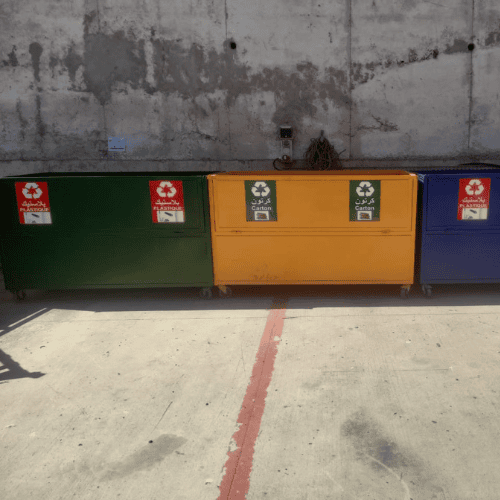 Gestion des déchets 64 Une vue similaire des trois grands conteneurs de recyclage industriels de l'image précédente, alignés contre le même mur en béton. Le bac vert (à gauche) et le bac jaune (au centre) sont bien positio
