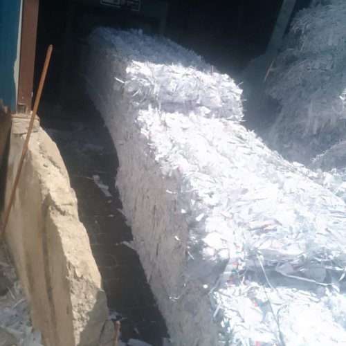 Gestion des déchets 67 Une scène d'intérieur d'entrepôt montrant une importante collection de déchets de papier blanc recyclé préparés pour le transport. Plusieurs grosses balles de papier blanc compactées sont alignées co